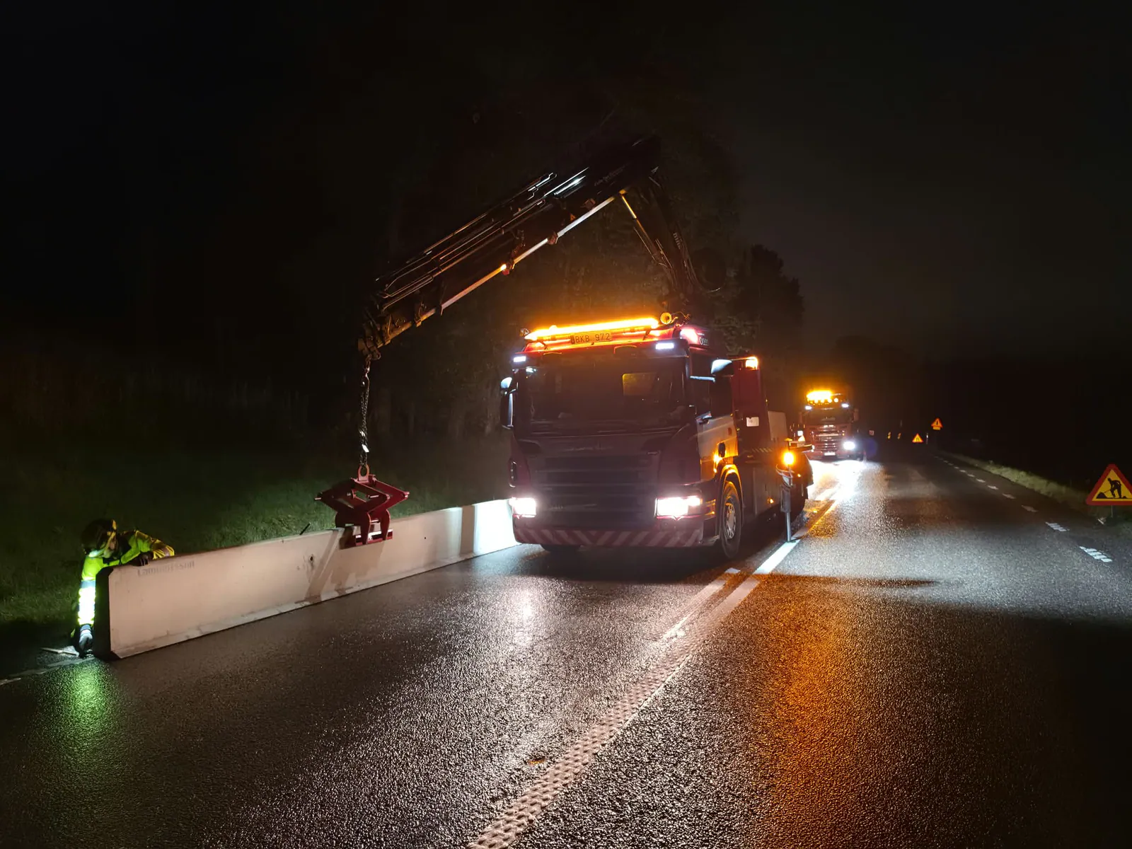 Kranbilen lyfter deltablock vid ett nattligt vägarbete